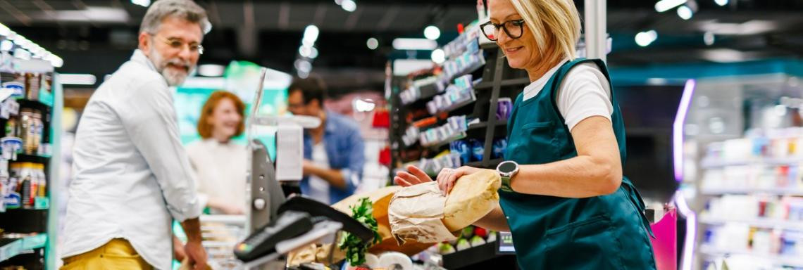 Mann kauft bei Kassiererin an einer Supermarktkasse ein