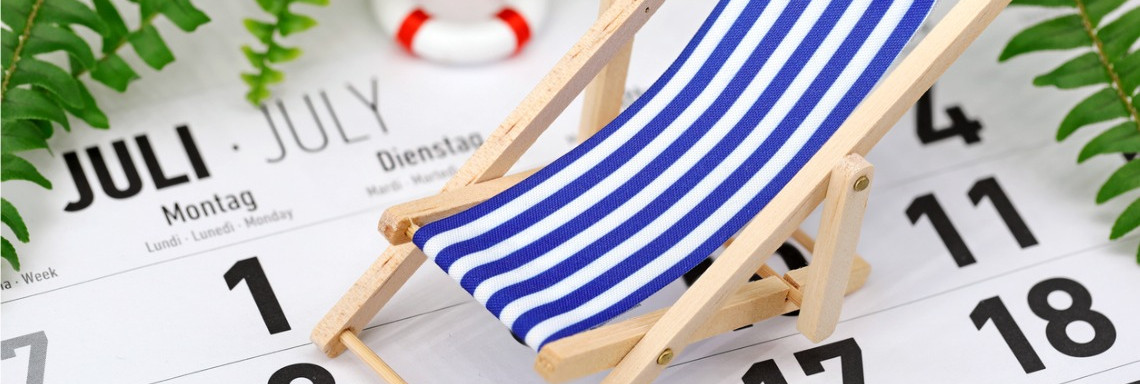 Nahaufnahme kleiner Spielzeug-Liegestuhl und -Schwimmring stehen auf Kalender