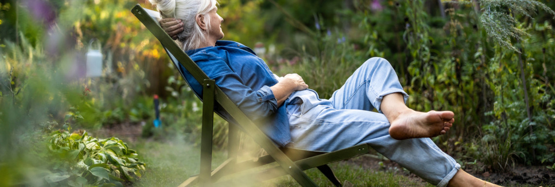 Mature woman relaxing in deckchair in her garden
