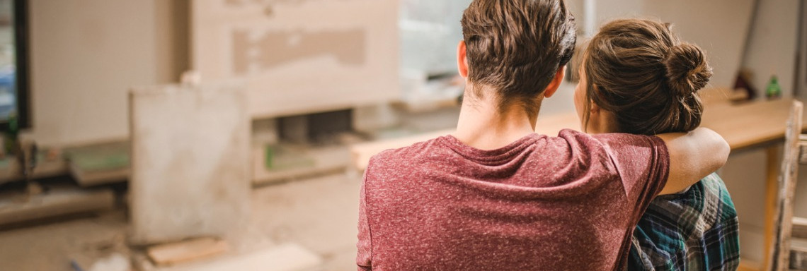 Junges Paar steht in neuer Wohnung auf Baustelle und schaut sie sich an