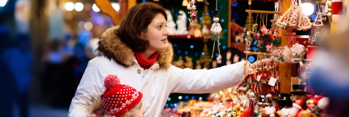Frau mit Kind an einem Stand mit Weihnachtsdeko auf dem Weihnachtsmarkt