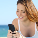 junge Frau mit Handy am Strand