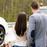 junges Paar sieht zu, wie ihr Auto abgeschleppt wird