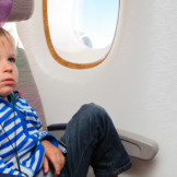 Kleinkind mit Kopfhörern im Flugzeug