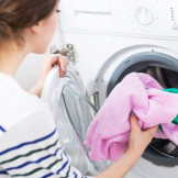 Waschen im Mietshaus: Junge Frau füllt Waschmaschine