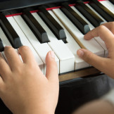 Nahaufnahme von Händen auf Klaviertastatur: Hausmusik