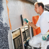 Sanierungskosten: Ein Mann verputzt eine Fassade.