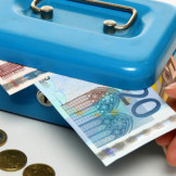 Diebstahl am Arbeitsplatz: Eine Hand, die einen 20-Euro-Schein aus einer gefüllten Geldkassette zieht.