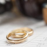 Scheidungskosten absetzen: Bei der Steuererklärung möglich? Zwei Eheringe liegen auf einem Dokument.
