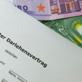 Geld verleihen: Wichtige Regeln beim Privatdarlehen. Euro-Scheine unter einem Zettel, auf dem 