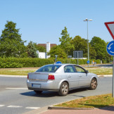 Vorfahrt im Kreisverkehr: Die Rechtslage. Ein silbernes Auto biegt in einen Kreisverkehr ein.