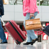 Handgepäck im Flugzeug: So viel dürfen Sie mitnehmen. Menschen ziehen ihre Koffer durch das Terminals eines Flugzeugs.