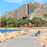 Strandhotel: Baustelle nicht immer ein Reisemangel. Eine Promenade, an deren Seiten große Steine aufgeschichtet sind, im Hintergrund sieht man mehrere Hotelkomplexe.