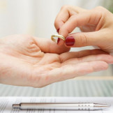 Einvernehmliche Scheidung: Diese Vorteile bietet sie. Eine Frau mit roten Fingernägeln legt einen Ehering in die Hand eines Mannes.