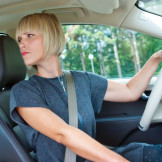 Rückwärtsfahren: Das erlaubt die StVO. Eine junge Frau sitzt im Auto und schaut nach hinten.