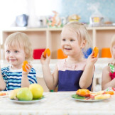 Kita-Essensgeld: Pauschale darf nicht zu hoch sein. Mehrere Kleinkinder sitzen an einem Tisch und essen Obst.
