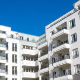 Hausverwaltung: Diese Aufgaben hat sie laut Gesetz. Eine moderne Wohnsiedlung mit weißer Fassade und Balkonen.