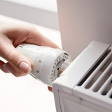 Heizperiode: Mietrecht regelt das Recht auf Wärme. Eine Frauenhand dreht am Thermostatkopf einer Heizung.