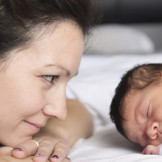 Verbotene Vornamen: Wie Kinder nicht heißen dürfen. Eine Mutter schaut beseelt ihr schlafendes Neugeborenes an.