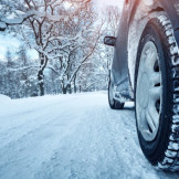 Winterdienst: Außerorts keine flächendeckende Streupflicht. Der Hinterreifen eines Autos auf einer schneebedeckten Straße.