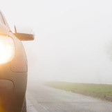 Beleuchtung am Auto: Korrekte Benutzung und Bußgelder. Das Vorderlicht eines Autos, das auf einer Landstraße fährt.