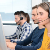 Frau und mehrere Männer in einem Callcenter vor dem Rechner