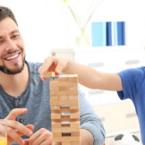 Mann und Junge bauen einen Turm aus Holzstäben
