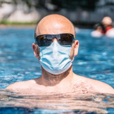 Mann mit Munschutz im Swimming-Pool