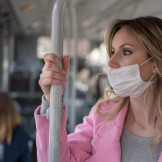 Frau mit Mund-Nasenschutz steht im Bus