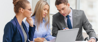 Drei Arbeitnehmer gucken auf einen Laptop Drei Arbeitnehmer gucken auf einen Laptop