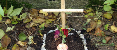 Tierbestattung im Garten: Holzkreuz auf einem Haustiergrab Tierbestattung im Garten: Holzkreuz auf einem Haustiergrab