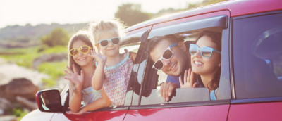 Was ist eine Pauschalreise? Definition und BGB-Regelung. Ein junge Familie, bestehend aus Eltern und zwei Mädchen, winken aus einem kleinen roten Auto. Alle tragen Sonnenbrillen. Was ist eine Pauschalreise? Definition und BGB-Regelung. Ein junge Familie, bestehend aus Eltern und zwei Mädchen, winken aus einem kleinen roten Auto. Alle tragen Sonnenbrillen.