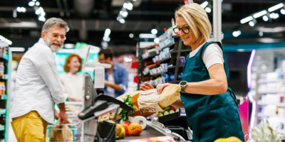 Mann kauft bei Kassiererin an einer Supermarktkasse ein