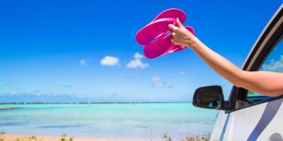 Barfuß Auto fahren: Frau hält Flip Flops aus dem Autofenster