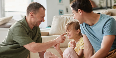 Männliches Paar mit Mädchen Pflegekind auf dem Sofa