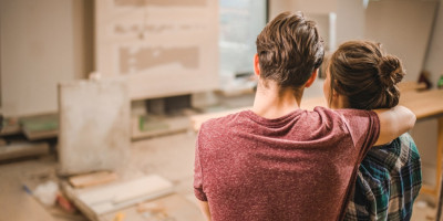 Junges Paar steht in neuer Wohnung auf Baustelle und schaut sie sich an