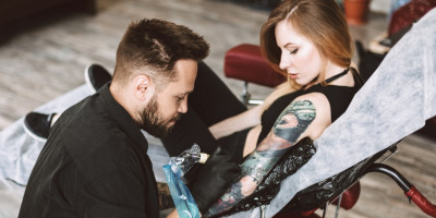 Tattoo Artist sticht Frau im Studio ein Tattoo auf dem Arm