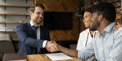 Businessmann schüttelt Paar über Vertrag die Hand