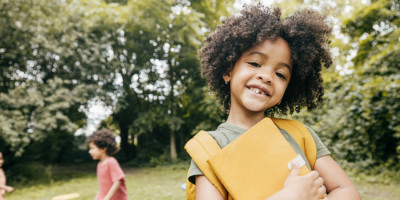 Mädchen mit Schulsachen lächelt in die Kamera