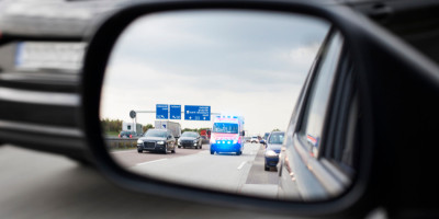 Autos Rettungswagen und Rettungswagen auf Autobahn im Autospiegel