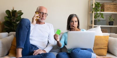 Paar auf dem Sofa mit Handy, Laptop und Kreditkarte