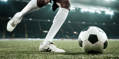 Nahaufnahme von Fußballerbeinen, die im Stadion einen Ball wegschießen