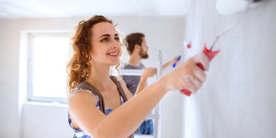 glückliche Frau streicht Wand