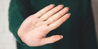 Frau hält eine Hand abwehrend vor sich.
