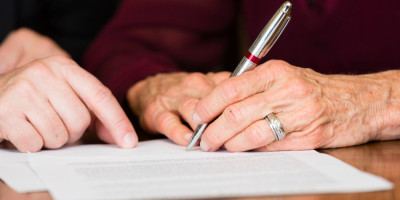 Alte Person unterschreibt Testament