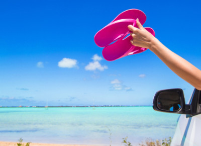 Barfuß Auto fahren: Frau hält Flip Flops aus dem Autofenster Barfuß Auto fahren: Frau hält Flip Flops aus dem Autofenster