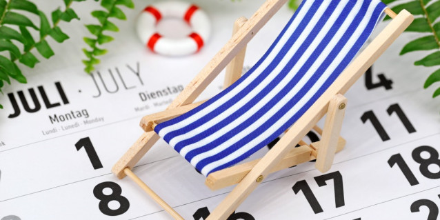 Nahaufnahme kleiner Spielzeug-Liegestuhl und -Schwimmring stehen auf Kalender