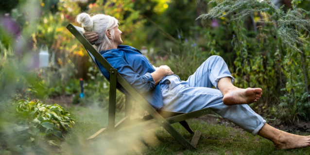 Mature woman relaxing in deckchair in her garden