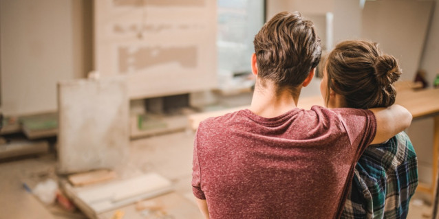 Junges Paar steht in neuer Wohnung auf Baustelle und schaut sie sich an