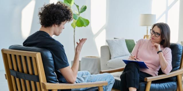 Psychotherapeutin und Patientin sitzen sich auf Stühlen gegenüber bei Therapiestunde